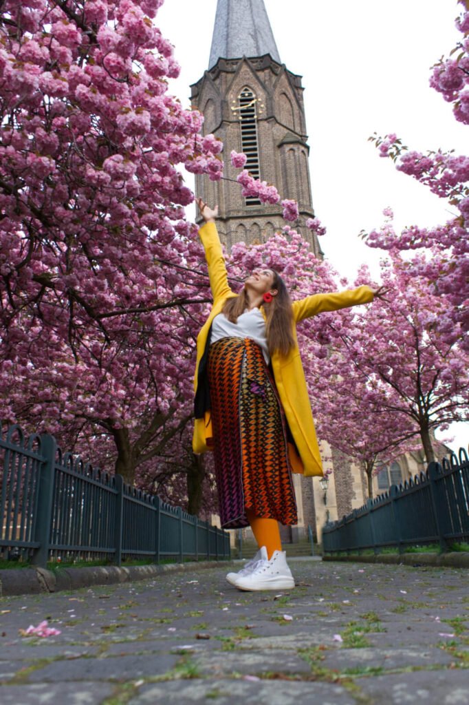 Pregnant Colorful Carmen Mar Happy Yoga Pose in from of cherry blossom tree 
