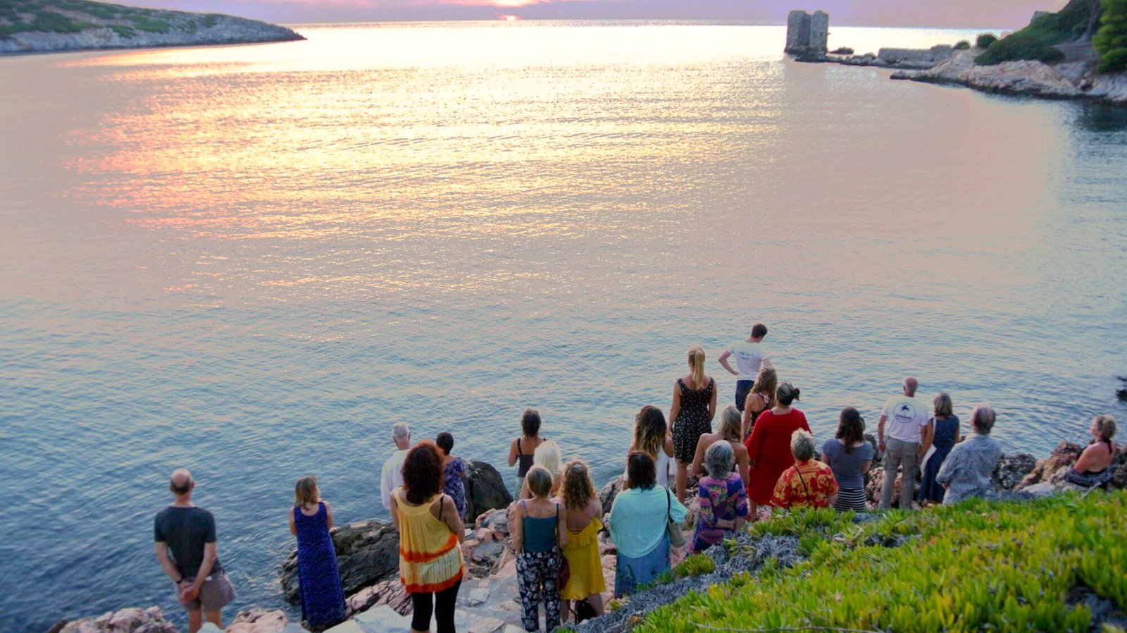 Meditation group watching towards the ocean in sunset scene